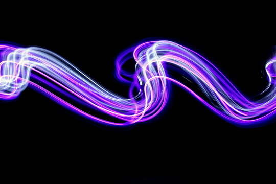 Long exposure photograph of neon pink and purple colour in an abstract swirl, parallel lines pattern against a black background. Light painting photography.