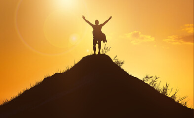 Business and success, leadership and achievement people concept. Silhouette of man on mountain top over sunset sky background. Hands up photo