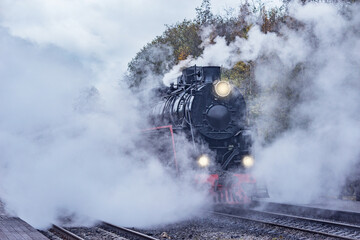 Fototapeta na wymiar Retro steam train departs from the station wooden platform.