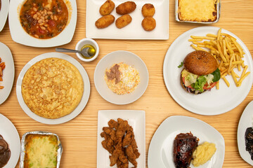 Top view image of Spanish food tapas and Mediterranean appetizers. Spanish omelette, Russian salad, chicken fingers, lasagna, roast pork knuckle, serrano ham croquettes