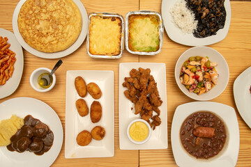 Top view image of tapas and Mediterranean dishes, seafood salpicon with prawns, squid in nera sauce, beef meatloaf, potato omelette, fried chicken and olive oil