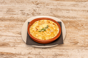 Gnocchis of mashed potatoes cooked with nutmeg and four cheeses with basile in a clay pan