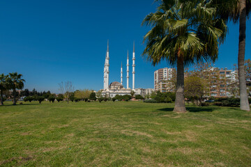 Impressive white Ottoman architecture mosque with 6 towering minarets seen from the surrounding park