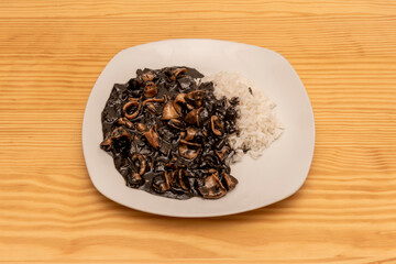 Typical recipe from the north of Spain with squid with ink sauce and white rice garnish