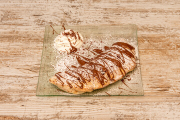 Italian calzone dessert filled with cream and nutella with glass sugar on transparent glass plate...