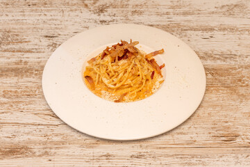 Delicious spaghetti dish with carbonara sauce and guanciale with grated parmesan cheese on white plate