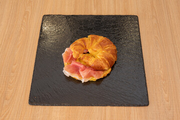 Hot butter croissant filled with Serrano ham ready for a good breakfast