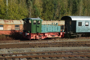 Fototapeta na wymiar Alte grüne Rangierlokomotive auf einem Abstellgleis. Viele alte Fahrgastwagen sind zu sehen. 