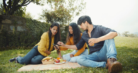 Indian friends having a picnic in a garden surrounded by trees