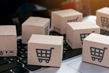 Online shopping - Paper cartons or parcel with a shopping cart logo on a laptop keyboard. Shopping service on The online web and offers home delivery..