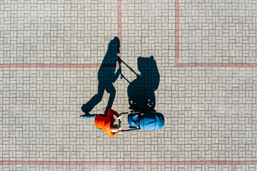 Aerial view of parent with a stroller on a walk during sunny day, perspective directly above