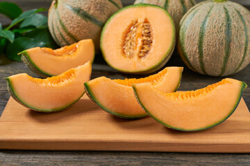 ripe sweet cantaloupe melon on wood plate and old wooden background.
