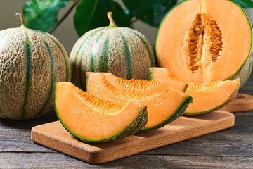 sliced cantaloupe melon on wood plate and old wooden background.
