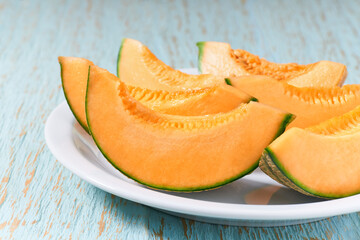 Naklejka na ściany i meble Sliced ripe melon in a ceramic plate on a wooden table.