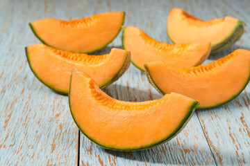 sliced ripe cantaloupe melon on a blue wooden table, selective focus.