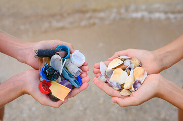 Rubbish and seashells in hands. View from above. Ecology concept