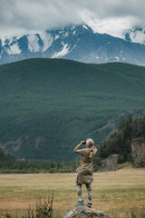 Fototapeta na wymiar Girl with binoculars standing in the mountains of the Altai Republic