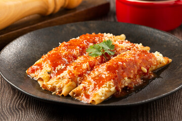 Pancakes stuffed with minced meat and topped with tomato sauce and grated cheese.