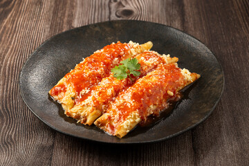 Pancakes stuffed with minced meat and topped with tomato sauce and grated cheese.