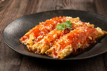 Pancakes stuffed with minced meat and topped with tomato sauce and grated cheese.