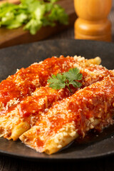 Pancakes stuffed with minced meat and topped with tomato sauce and grated cheese.