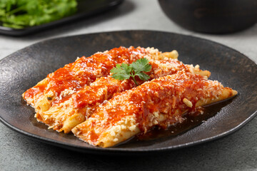 Pancakes stuffed with minced meat and topped with tomato sauce and grated cheese.