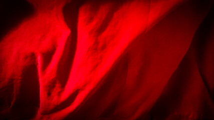 An abstract red background made of fabric that erratically fluctuates from the wind.