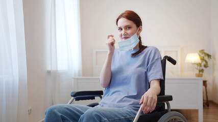 A young disabled woman is putting off a protective mask