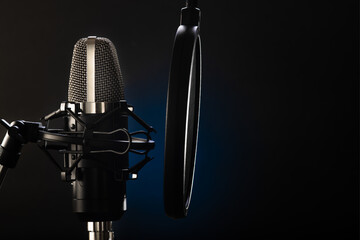 Professional microphone with a pop filter on a black and blue background. Macro photography....