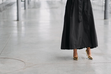 Female in a long black skirt and gold heels in a white room