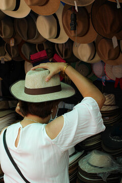 Mujer poni&eacute;ndose un sombrero de espaldas