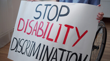 A disabled young woman is showing a poster and talking to the camera