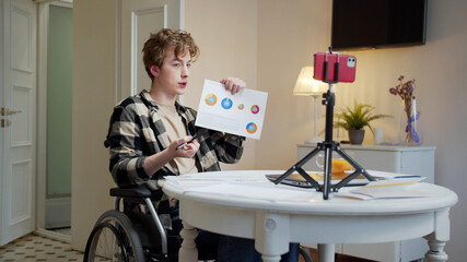 A disabled young man is talking with someone and showing diagrams 