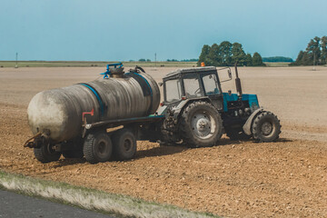 Tractor with a barrel of fertilizer in the field. Agricultural equipment and industrial work on the...
