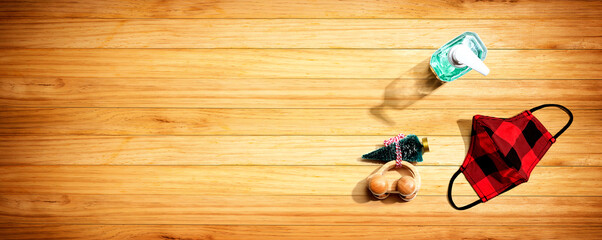 Face mask and a sanitizer bottle with a toy car carrying a Christmas tree - flat lay