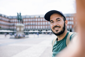 Young backpacker tourist taking selfie photo with smartphone outdoors - Happy man visiting Plaza...