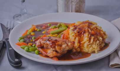 Chicken dinner with vegetables and gravy.