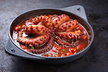 Traditional Italian polpo alla griglia in salsa di pomodoro with barbecued octopus in tomato sauce served as close-up on a modern design saucepan