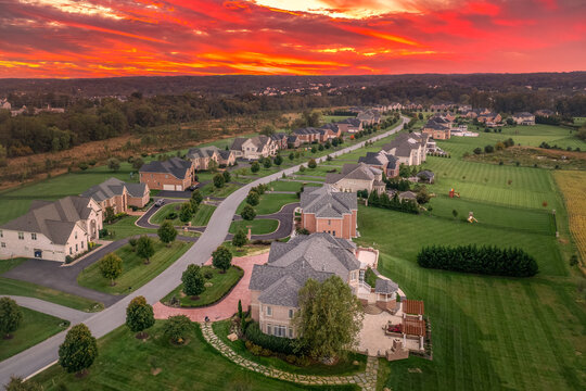 Aerial view of new construction winding dead-end street lined with luxury houses, large lots,  in upper class neighborhood American real estate development in the USA with stunning sunset orange sky