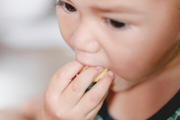 Close-up of cute baby boy face enjoying eating snacks.