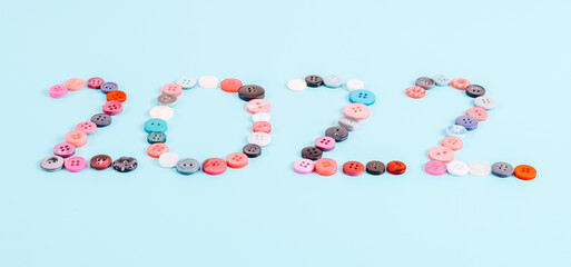 Number 2022 from multi-colored buttons on light blue.