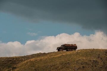 A lumber truck stands on a mountain against a blue sky and clouds
