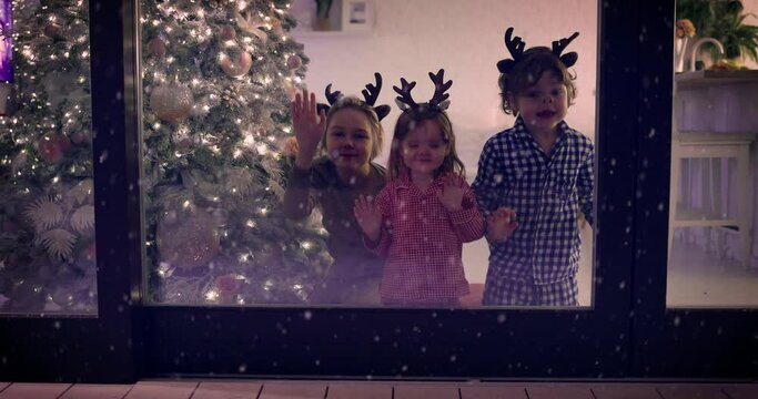 cute kids (one is funny) watching the snowflakes falling on the patio at magical Christmas night