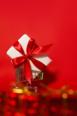 a huge gift with a red ribbon in a shopping cart with some bokeh. Place for text. Mockup