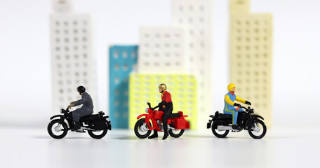 Three miniature motorcycle riders in front of a miniature building. Miniature people and miniature building.
