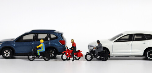 Concept about the dangers of speeding motorcycles. Miniature people and miniature car. Miniature motorcycle messenger between miniature cars. 
