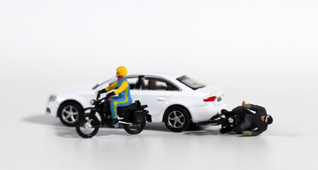 Miniature people and miniature car. White cars and fallen motorcycle riders. Concept about the dangers of speeding motorcycles.
