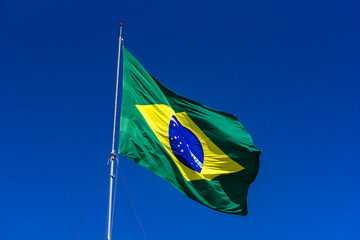 Brazilian flag hoisted with blue sky.