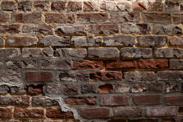 Red brick wall with numerous levels of  decay and repair, horizontal aspect
