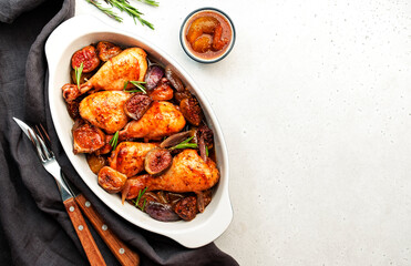 Baked chicken legs, drumsticks with figs and red onions in balsamic marinade in ceramic baking dish, white background, top view